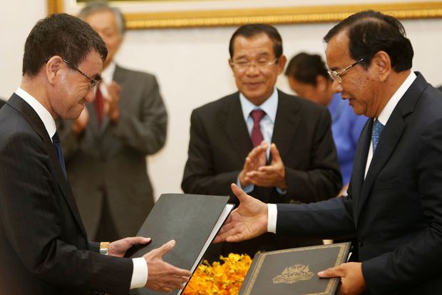 Japan's Foreign Minister Taro Kono (left) exchanges a document with his Cambodia's counterpart Prak Sokhonn as Cambodia's Prime Minister Hun Sen (centre) applauds after a signing ceremony in Phnom Penh on Sunday. (Reuters photo) Japan's Foreign Minister Taro Kono (left) exchanges a document with his Cambodia's counterpart Prak Sokhonn as Cambodia's Prime Minister Hun Sen (centre) applauds after a signing ceremony in Phnom Penh on Sunday. (Reuters photo)
