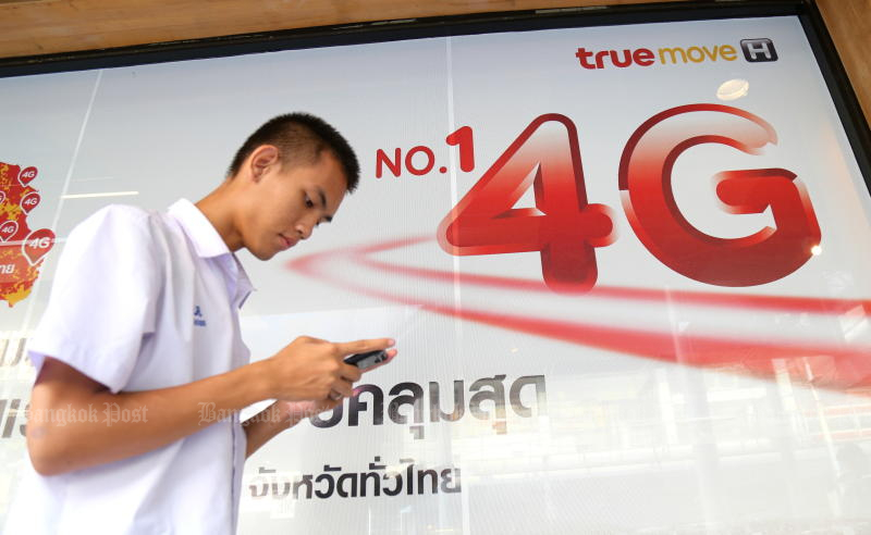 A student checks his mobile while walking past a billboard advertising True Move H’s 4G service. (Photo by Narupon Hinshiranan) A student checks his mobile while walking past a billboard advertising True Move H’s 4G service. (Photo by Narupon Hinshiranan)