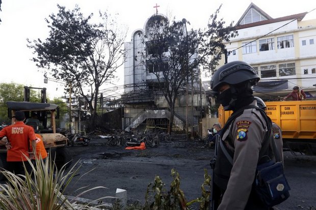 The body of a suicide bomber lies under an orange covering (background) as police secure the site of a terrorist attack on one of several churches bombed on Sunday in Surabaya. (AP photo) The body of a suicide bomber lies under an orange covering (background) as police secure the site of a terrorist attack on one of several churches bombed on Sunday in Surabaya. (AP photo)