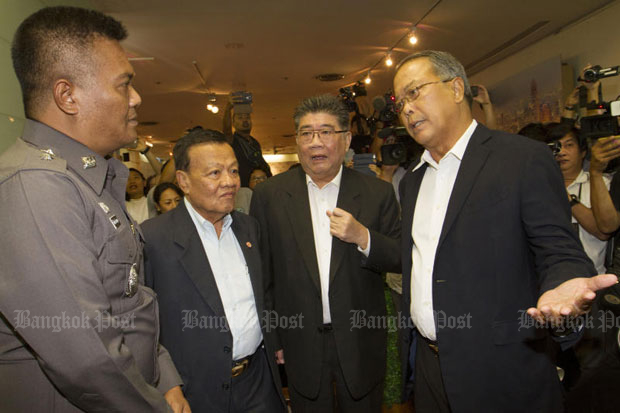 Pheu Thai's Chusak Sirinil, right, talks to a police officer sent to warn the party not to hold a press conference at its headquarters in Bangkok on Thursday morning. Acting Pheu Thai leader Viroj Pao-in, second left, and acting Pheu Thai secretary-general Phumtham Vejjayachai look on. (Photo by Pawat Laopaisarntaksin)