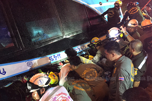 Rescuers help to extract stranded passengers from the double-decker bus that turned upside down in Khlong Luang district in Pathum Thani on Sunday morning. (Photo by Pongpat Wongyala)