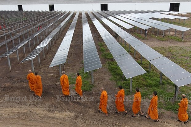 Monks walk past a solar farm on their way to the temple after morning alms rounds. The latest version of a 20-year energy plan increases the importance of renewable energy. (File photo)