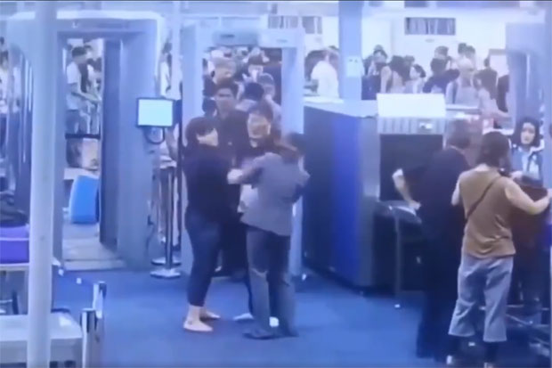 A security officer gets a slap on the face from a departing traveller during a second metal detector scan at Suvarnabhumi airport late on Saturday night. (Photo captured from a video clip)