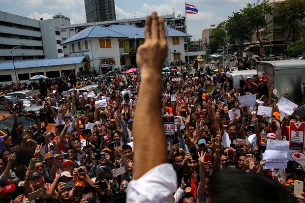 Thanathorn Juangroongruangkit, leader of the Future Forward Party, and his supporters flash three-finger salutes as he leaves a police station after hearing a sedition complaint filed by the army in Bangkok on April 6. (Reuters photo)