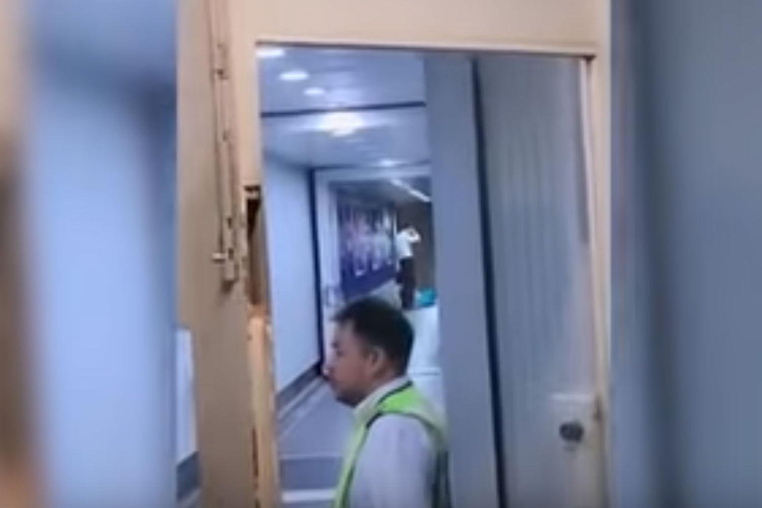 A screenshot captured from a video clip shows in the background an aviation officer talking to a person lying on the aerobridge allegedly causing a delay to a Shanghai-bound flight from Suvarnabhumi airport recently.