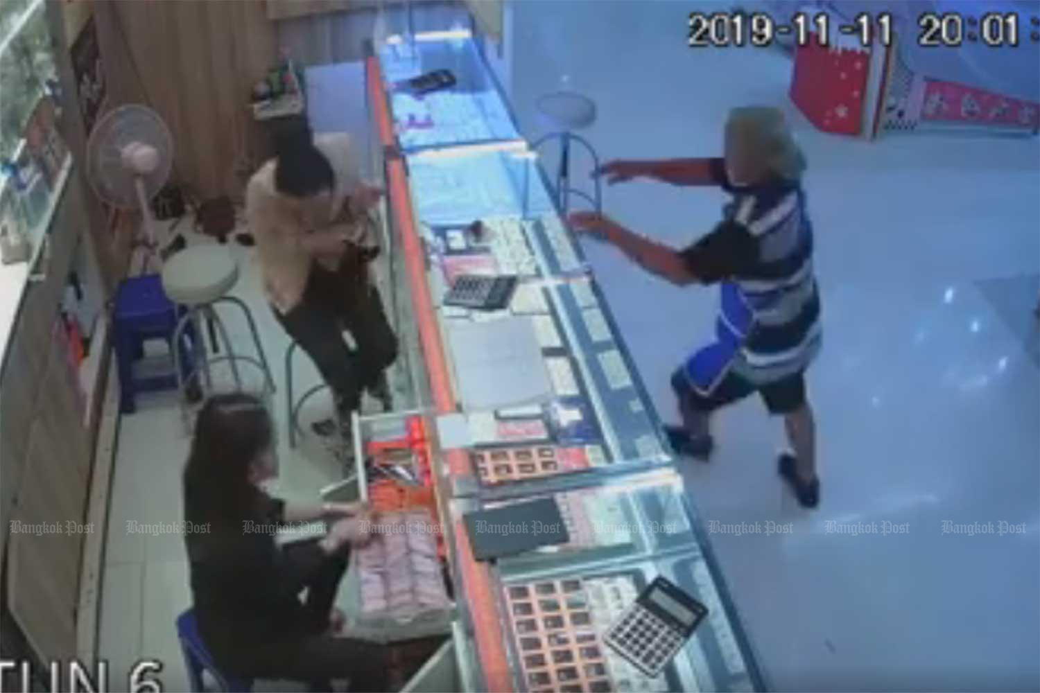 A man throws stones to smash display cabinets and steal gold from a shop at a Tesco Lotus superstore in Udon Thani on Monday night. (From video on udonthaniupdate Facebook page)