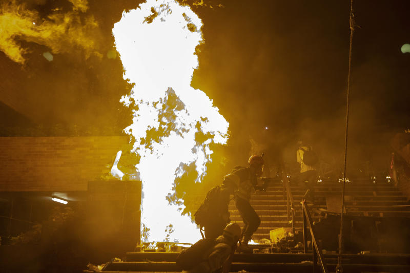 Medical volunteers run through fires at the Hong Kong Polytechnic University campus during the early morning hours in Hong Kong on Monday.(AP photo) Medical volunteers run through fires at the Hong Kong Polytechnic University campus during the early morning hours in Hong Kong on Monday.(AP photo)
