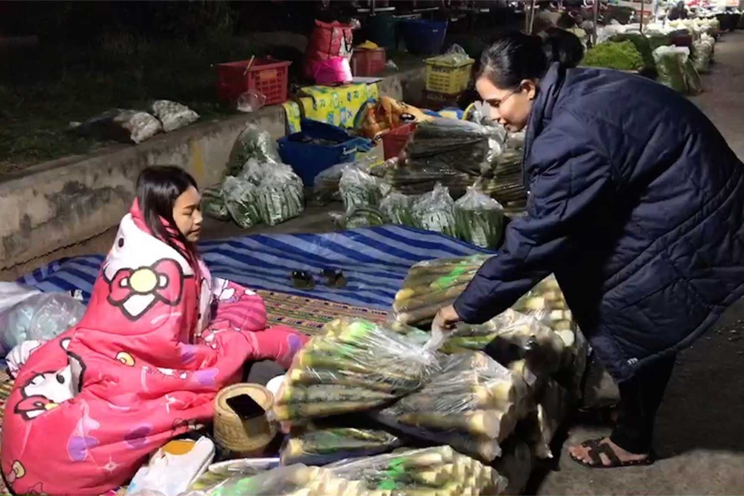 This vegetable vendor and her customer were well wrapped up against the cold at a market in Muang district of Kalasin province early on Tuesday. (Photo by Yongyuth Phuphuangpet) This vegetable vendor and her customer were well wrapped up against the cold at a market in Muang district of Kalasin province early on Tuesday. (Photo by Yongyuth Phuphuangpet)