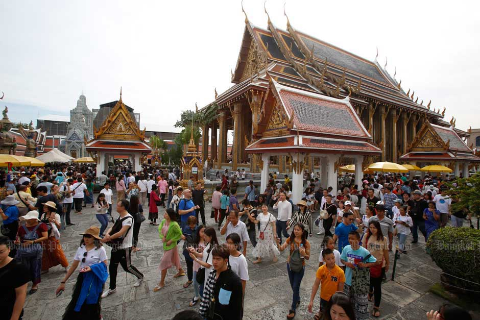 Local people and tourists visit the Temple of the Emerald Buddha in Bangkok on New Year's Day. — Pornprom Satrabhaya