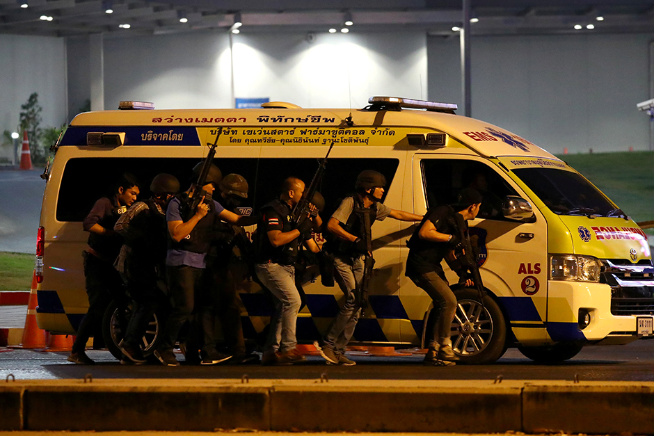 Security forces take cover behind an ambulance on Sunday. — Reuters