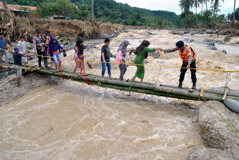 Police officers help people cross an emergency bridge over the Cidurian river in Bogor, Indonesia, on Friday. (Antara Foto/Arif Firmansyah/ via REUTERS) Police officers help people cross an emergency bridge over the Cidurian river in Bogor, Indonesia, on Friday. (Antara Foto/Arif Firmansyah/ via REUTERS)