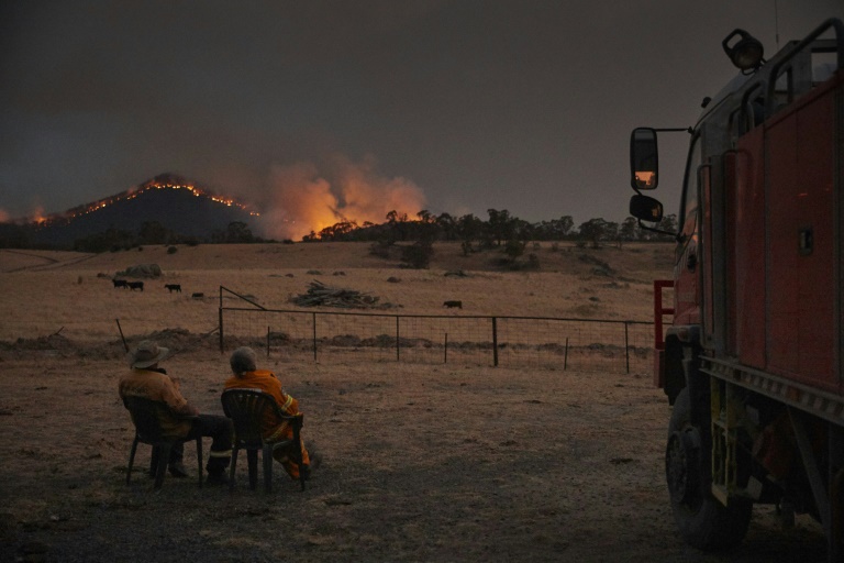 Volunteer firefighters watch as a bushfire rages on the outskirts of the town of Tumbarumba in New South Wales. Volunteer firefighters watch as a bushfire rages on the outskirts of the town of Tumbarumba in New South Wales.