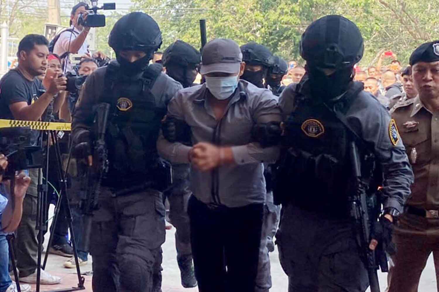 Police commandos escort robbery-murderer suspect Prasittichai Khaokaew, 38, into the tourist police office in Lop Buri province on Wednesday. (Police photo)