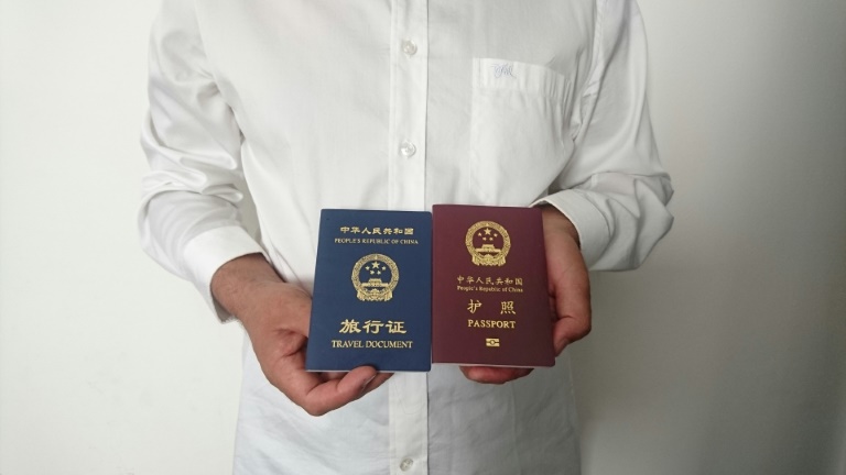 An unidentified Chinese Uighur man in the city of Medina holds his expired Chinese passport (red) and a one-way travel document (blue) issued in its place by the Chinese mission in Saudi Arabia. (AFP photo)