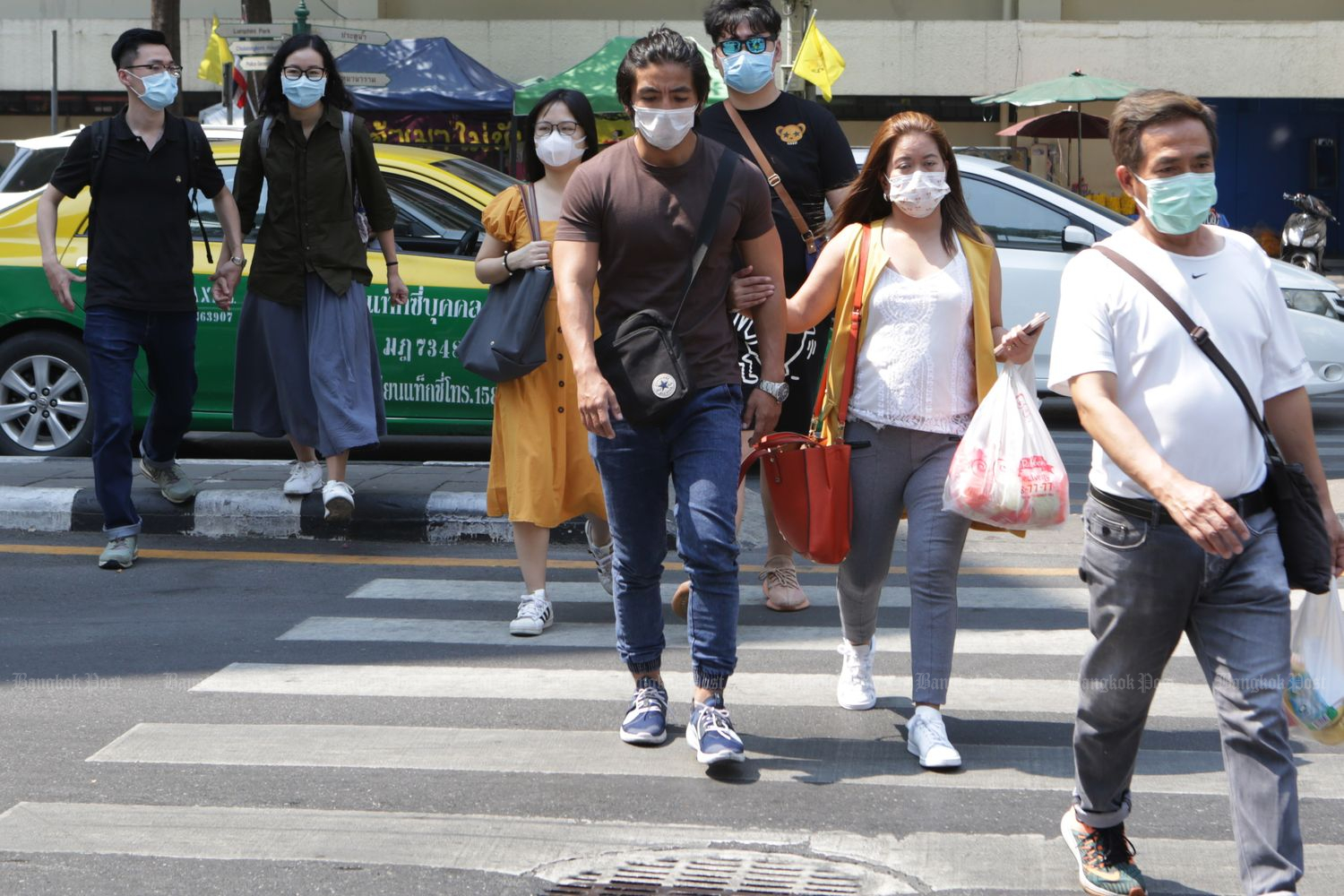 Tourists wear masks while shopping at the Ratchaprasong intersection in Bangkok on Saturday. (Photo by Apichit Jinakul)