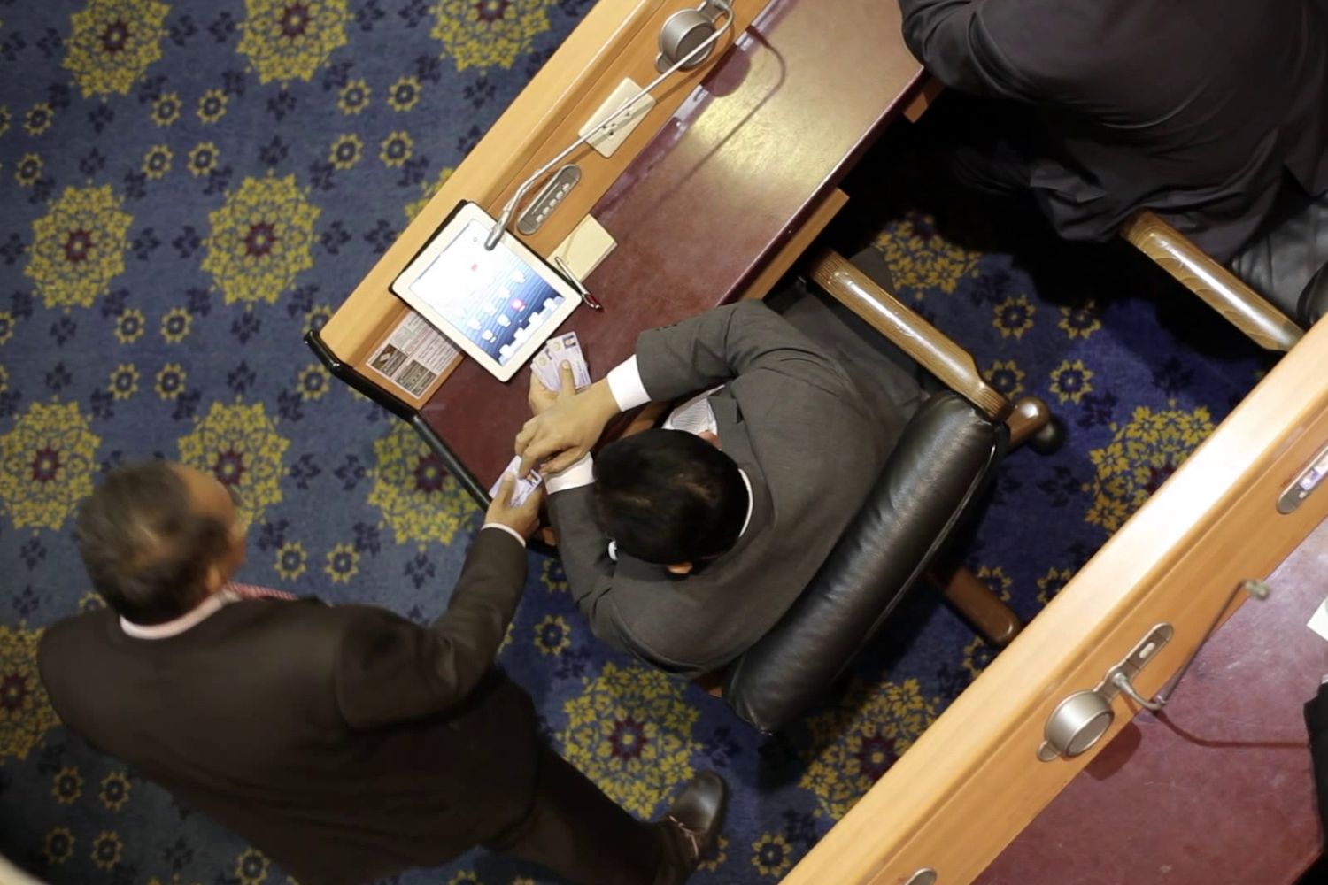 An MP is seen inserting a bunch of voting cards into a device during the vote on the 2020 budget bill in this screenshot captured from a video clip. An MP is seen inserting a bunch of voting cards into a device during the vote on the 2020 budget bill in this screenshot captured from a video clip.