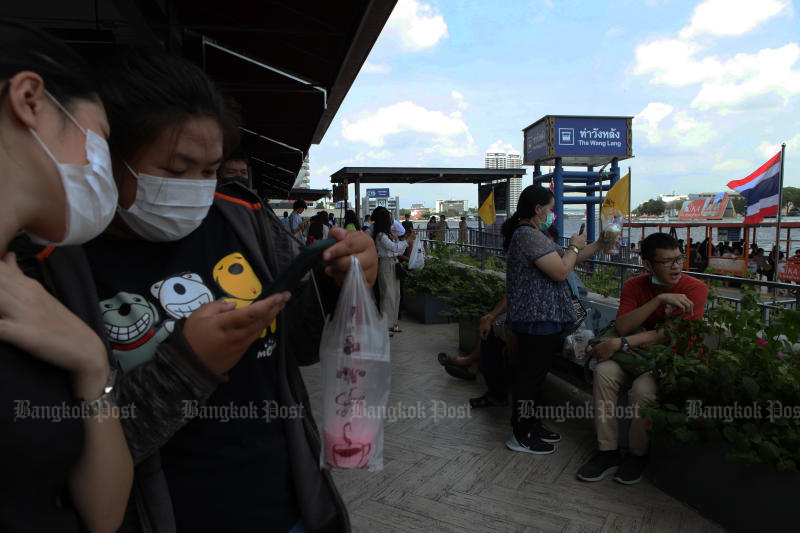 Commuters wear face masks while waiting for a boat to cross the Chao Phraya River at Wang Lang pier on Saturday. (Photo: Arnun Chonmahatrakool)