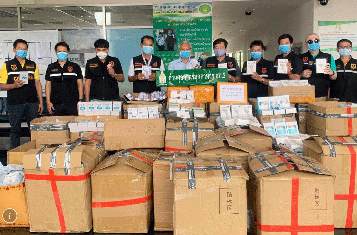 Customs officials display some of the nearly 1,900 boxes containing untaxed face masks, thermometers and other protective gear seized on Friday from a transport firm in Mukdahan. (Photo by Churoj Triprapakorn)