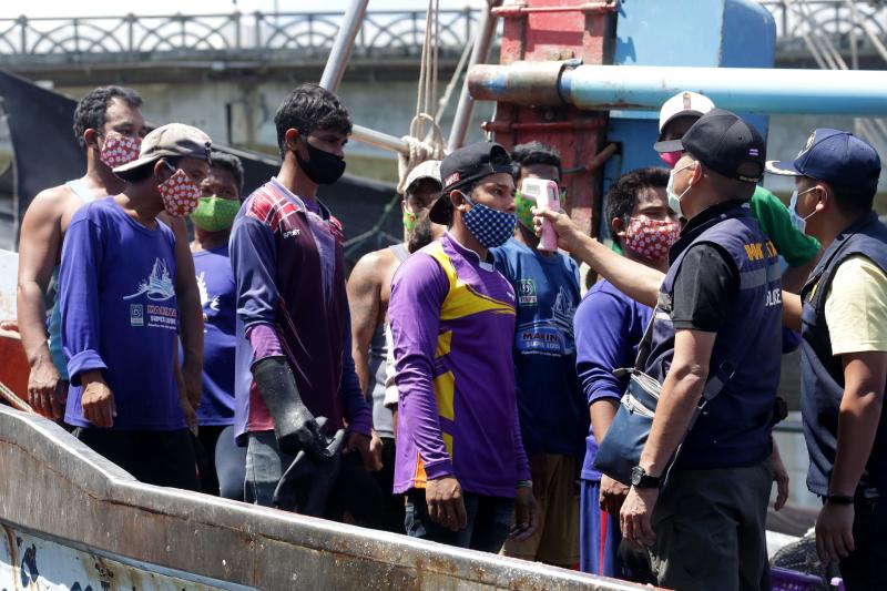 Immigration officers check the temperatures of Myanmar fisherman, as a preventive measure against the spread of the Covid-19 novel coronavirus, at the port in Pattani on Saturday. (AFP photo)