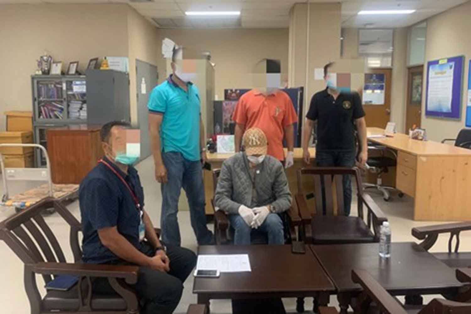 A suspect in the Forex-3D Ponzi scheme, seated right, in his apartment on Ratchadapisek road when he was arrested by Department of Special Investigation officials on Tuesday. (DSI photo)