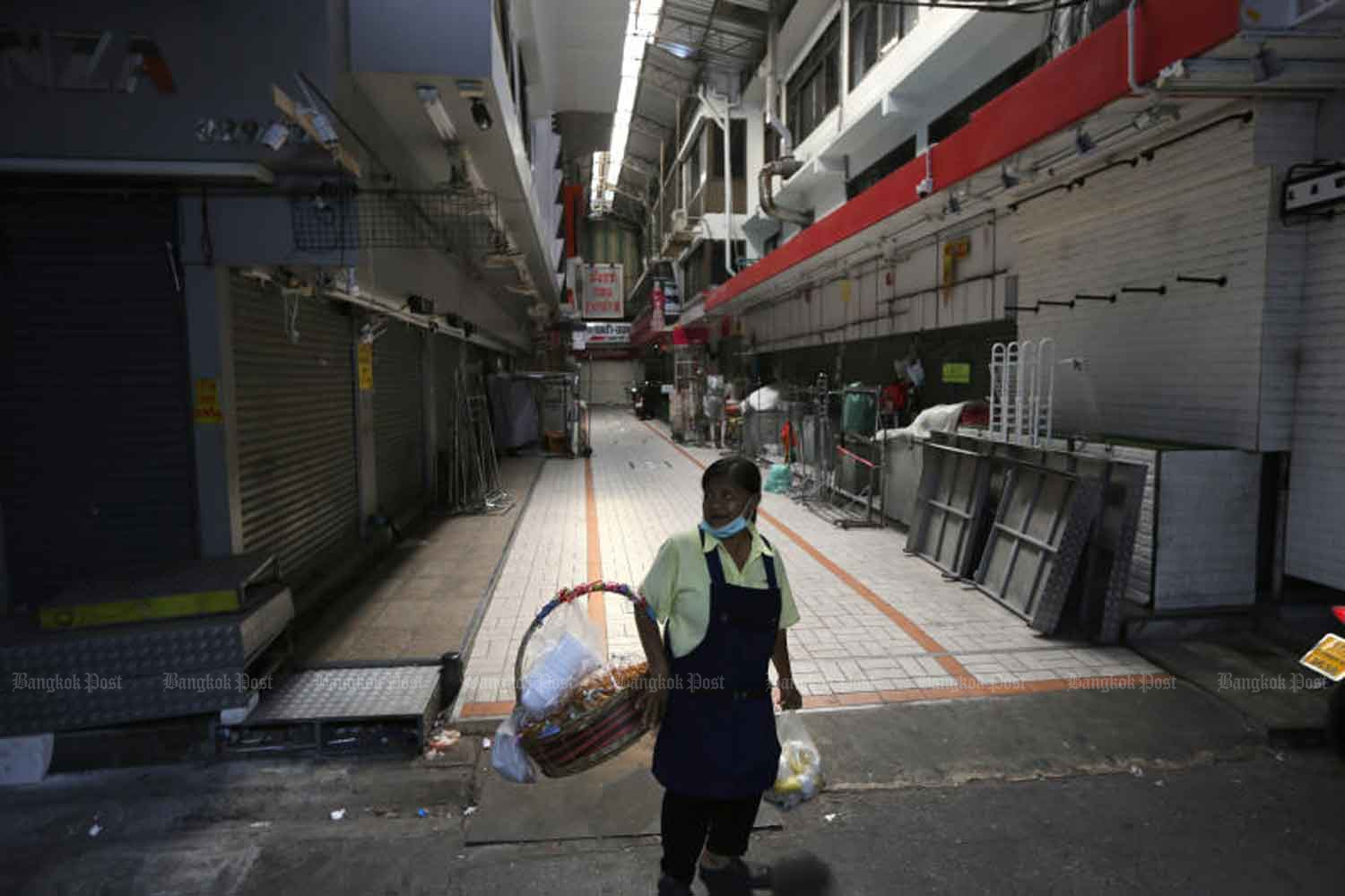 A woman looks on at a quiet market in Bangkok where all shops are closed. A government spokesperson has dismissed the possibility of quick relaxation of disease control measures that are restricting people's everyday life. (Photo: Wichan Charoenkiatpakul)