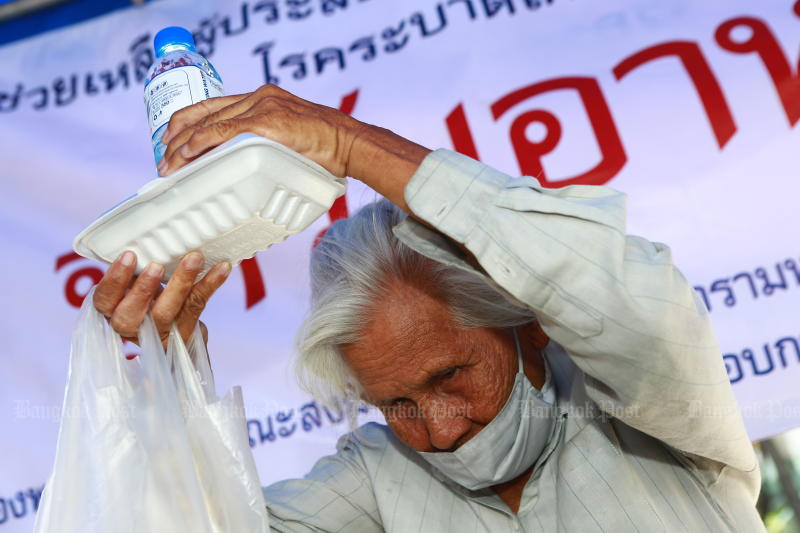 A woman receives a bag of food and essential supplies on April 8, 2020 at Wat That Thong in Bangkok’s Watthana district. The hand-out is part of an initiative of the Supreme Patriarch to help those in need during Covid-19 pandemic. (Photo by Somchai Poomlard)