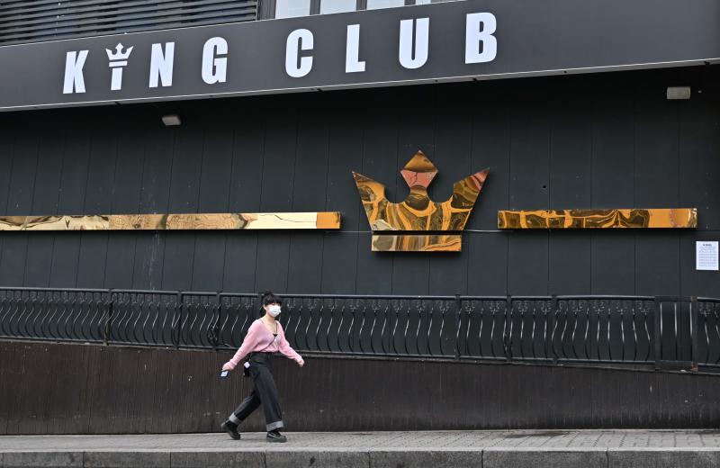 A woman wearing a face mask walks past a night club, now closed following a visit by a confirmed coronavirus patient, in the popular nightlife district of Itaewon in Seoul on Sunday. (AFP photo) A woman wearing a face mask walks past a night club, now closed following a visit by a confirmed coronavirus patient, in the popular nightlife district of Itaewon in Seoul on Sunday. (AFP photo)