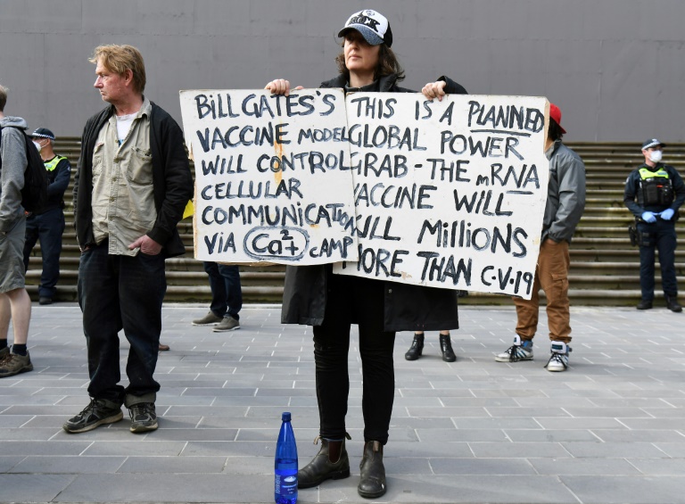 An anti-lockdown protester holds placards on the steps of Victoria's state parliament in Melbourne.