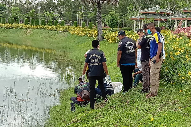 Rescue volunteers wrap the body of the baby in white cloth after he was retrieved from a park pond at Walailak University on Nakhon Si Thammarat on Monday. (Photo: Nujaree Raekrun)