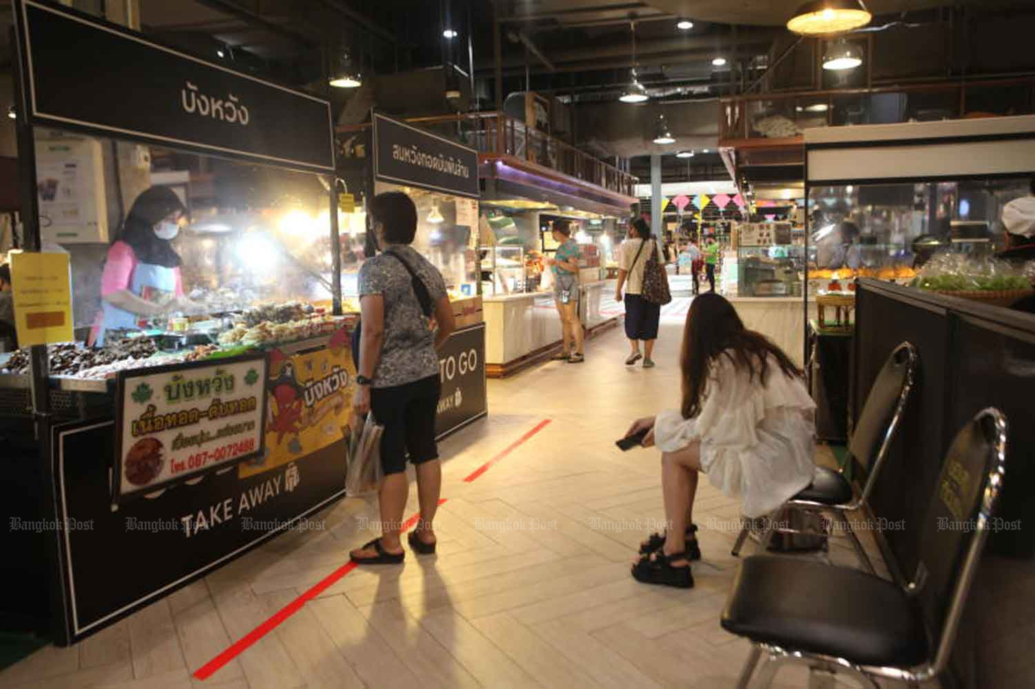 People buy food at CentralFestival EastVille shopping centre in Bangkok on Wednesday. The government will on Friday launch a new phone app to facilitate disease control at shops. (Photo: Arnun Chonmahatrakool)