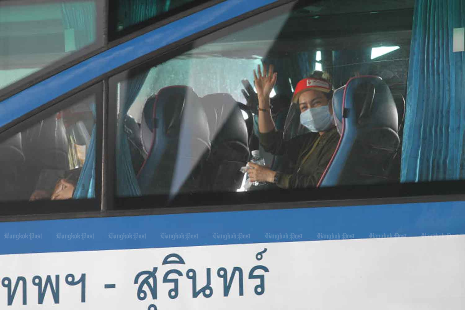 A Thai returnee from India waves to photographers at Suvanabhumi airport before being taken to 14-day quarantine at premises in Samut Prakan province on Thursday. (Photo: Nutthawat Wicheanbut)