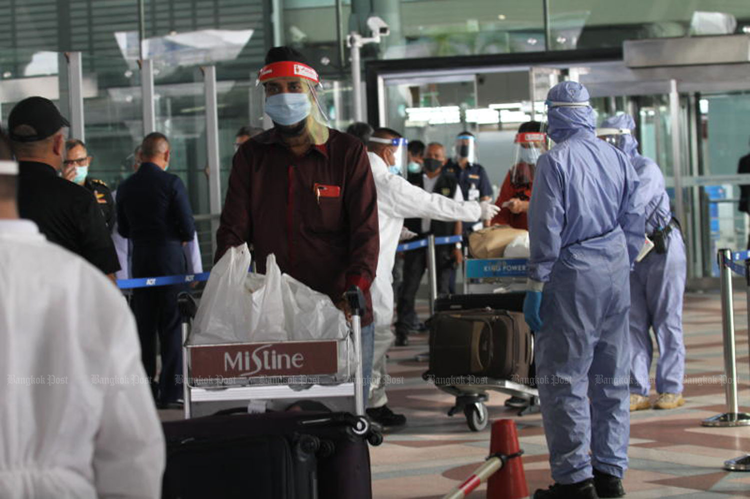 Officials check 35 Thai passengers returning from India at Suvarnabhumi airport on Wednesday. They were taken to a hotel in Samut Prakan to be quarantined. One of them had a fever and underwent a checkup at a local hospital. (Photo by Nutthawat Wicheanbut)