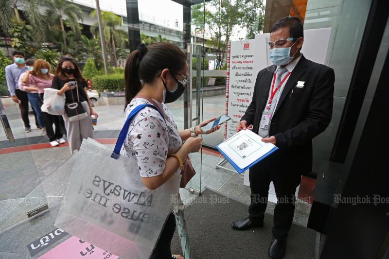 A shopper uses her mobile phone to scan the Thai Chana QR Code before entering The Mall Bang Kapi on May 17, 2020. (Photo by Varuth Hirunyatheb)