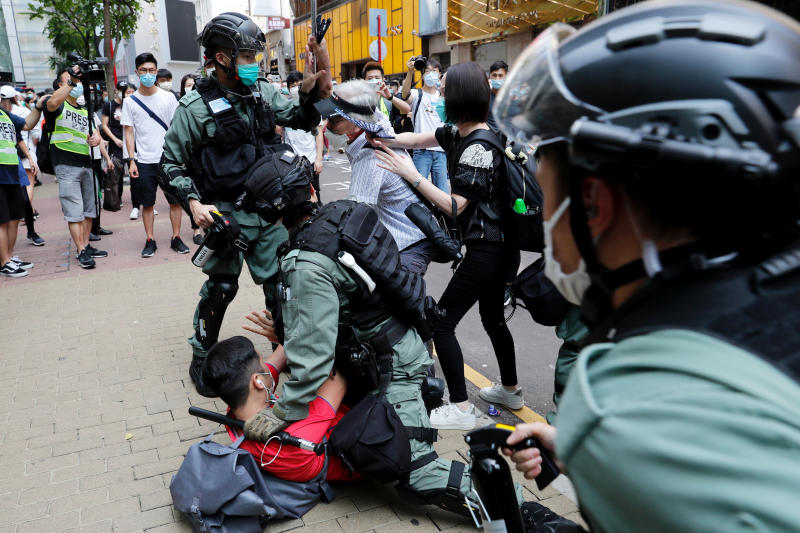 Anti-government demonstrators scuffle with riot police during a lunch time protest as a second reading of a controversial national anthem law takes place in Hong Kong on Wednesday