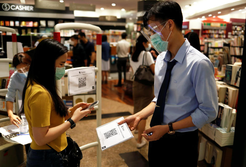 A woman wearing a protective mask scans a tracking system entering a bookstore inside a shopping mall in Bangkok on Friday. (Reuters photo)