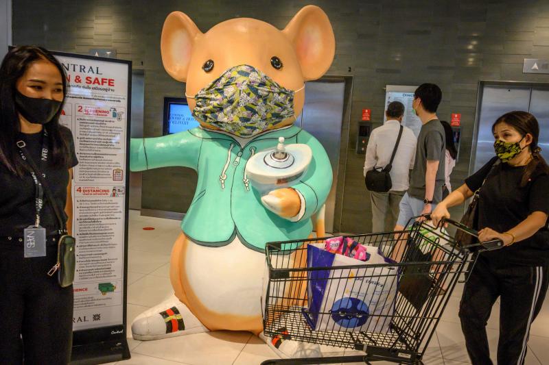 People walk in front of a giant mouse distributing hand sanitiser in a shopping mall in Bangkok on Sunday. (AFP photo)