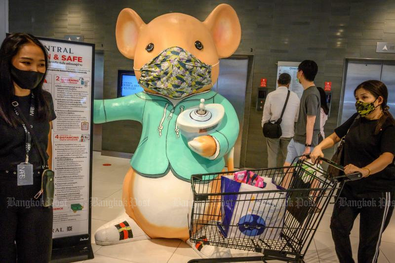 People walk in front of a giant mouse distributing hand sanitiser in a shopping mall in Bangkok on Sunday. (AFP photo)