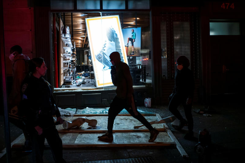 Protesters pass by a store looted after a march against the death in Minneapolis police custody of George Floyd, in the Manhattan borough of New York City on Tuesday. (Reuters photo)