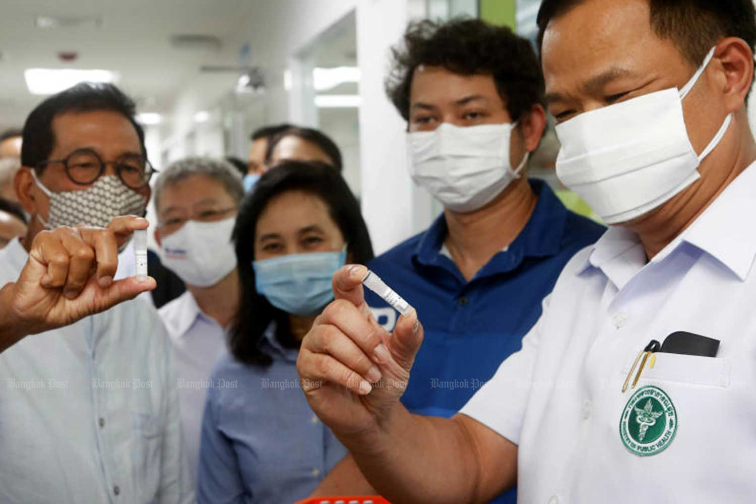 Pulic Health Minister Anutin Charnvirakul, right, looks at solution samples at the Siam Bioscience Group, which produces Covid-19 test kits, on June 1. (Photo: Pattarapong Chatpattarasill)