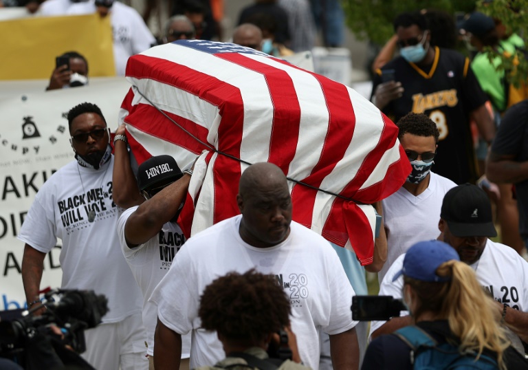Protesters carry an empty symbolic casket draped with an American flag during a Juneteenth march in Tulsa, Oklahoma Protesters carry an empty symbolic casket draped with an American flag during a Juneteenth march in Tulsa, Oklahoma
