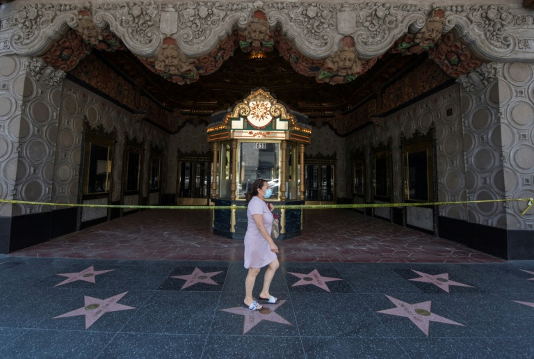 A woman walks past the famous El Capitan Theater in Hollywood, which remains closed due to the Covid-19 virus -- other theaters across the countries are reopening, and new releases will hit screens in July. A woman walks past the famous El Capitan Theater in Hollywood, which remains closed due to the Covid-19 virus -- other theaters across the countries are reopening, and new releases will hit screens in July.