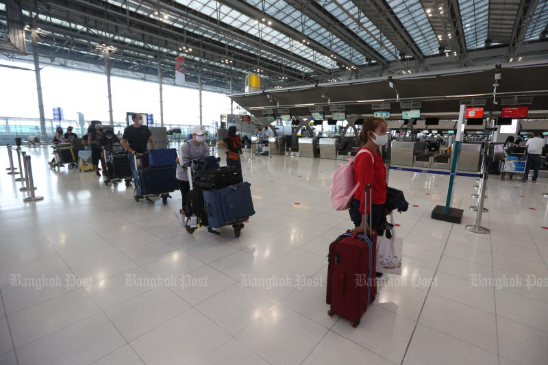 People wear face masks and observe social distancing as they queue up at a check-in counter at  Suvarnabhumi airport on June 15, 2020. (Photo by Varuth Hirunyatheb)