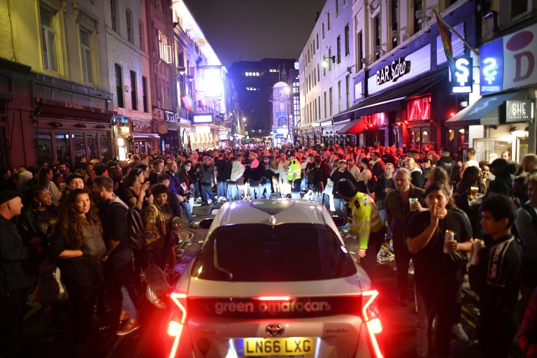 A car tries to drive along a street filled with people drinking in the Soho area of London. A car tries to drive along a street filled with people drinking in the Soho area of London.