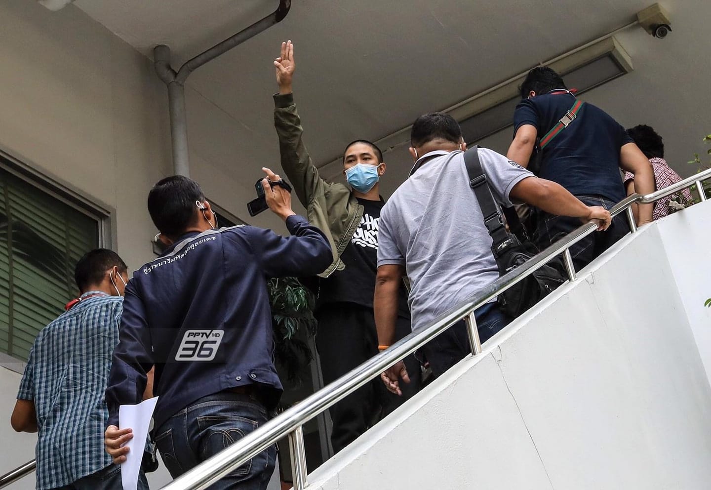 Dechathorn “Hockhacker” Bamrungmuang, a founder and member of 'Rap Against Dictatorship', shows a three-finger salute as he was taken to the Samran Rat police station on Thursday. He was among the five arrested on Thursday in connection with the July 18 rally. (Photo from Rap Against Dictatorship Facebook)