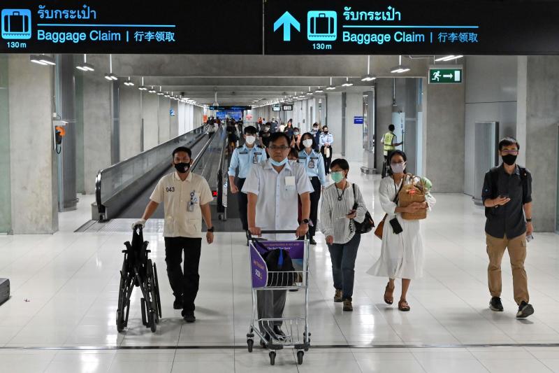 Passengers wearing face masks as a preventive measure against the Covid-19 coronavirus walk along a concourse at the departure area of Suvarnabhumi airport on Friday. (AFP photo)