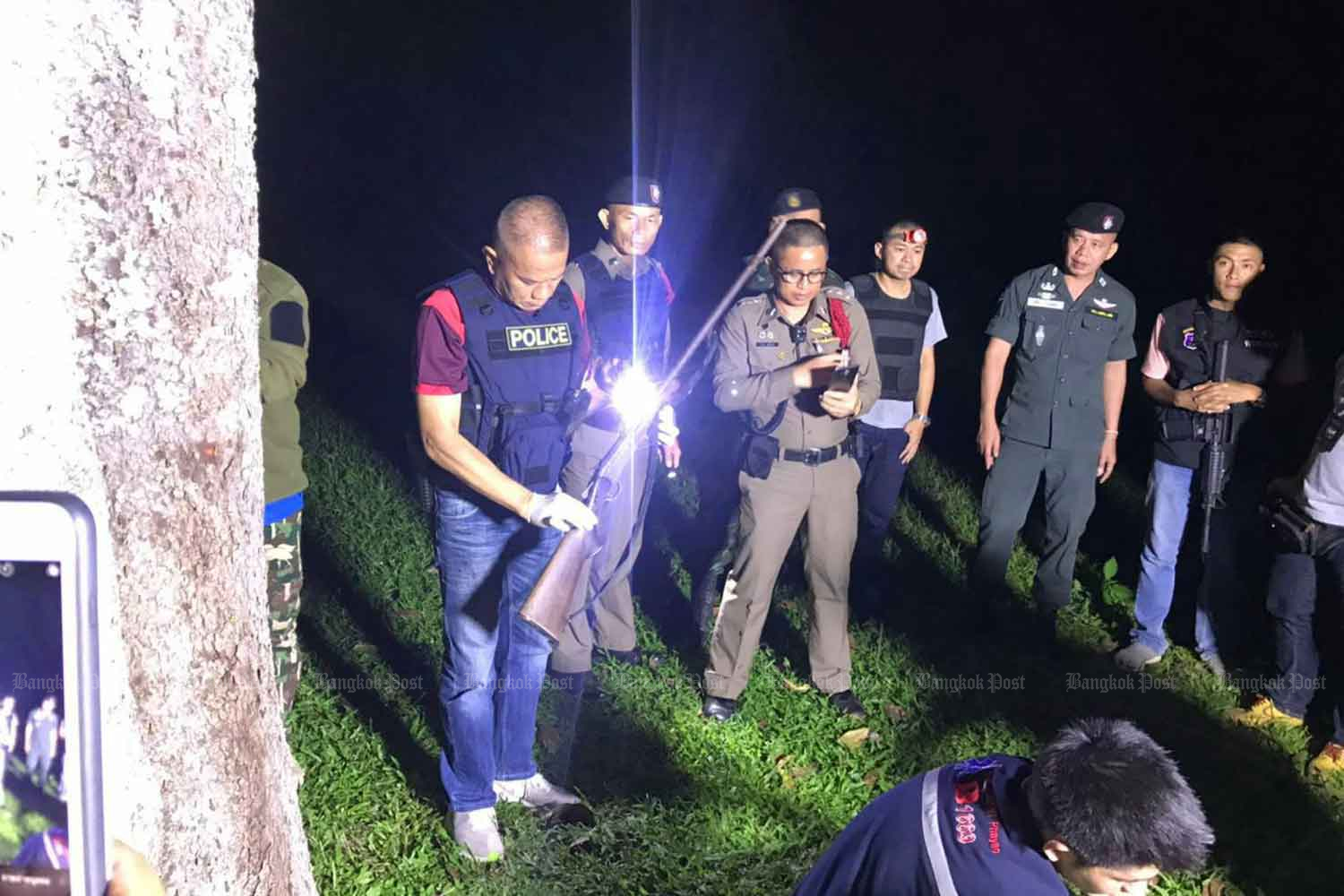 A police officer examines the shotgun used in the murder of three people at Ban Nong Ha in tambon Rom Yen, Chiang Kham district, Phayao, on Tuesday night. The killer then shot himself dead at the local helicopter landing pad. (Photo: Saiarun Pinaduang)