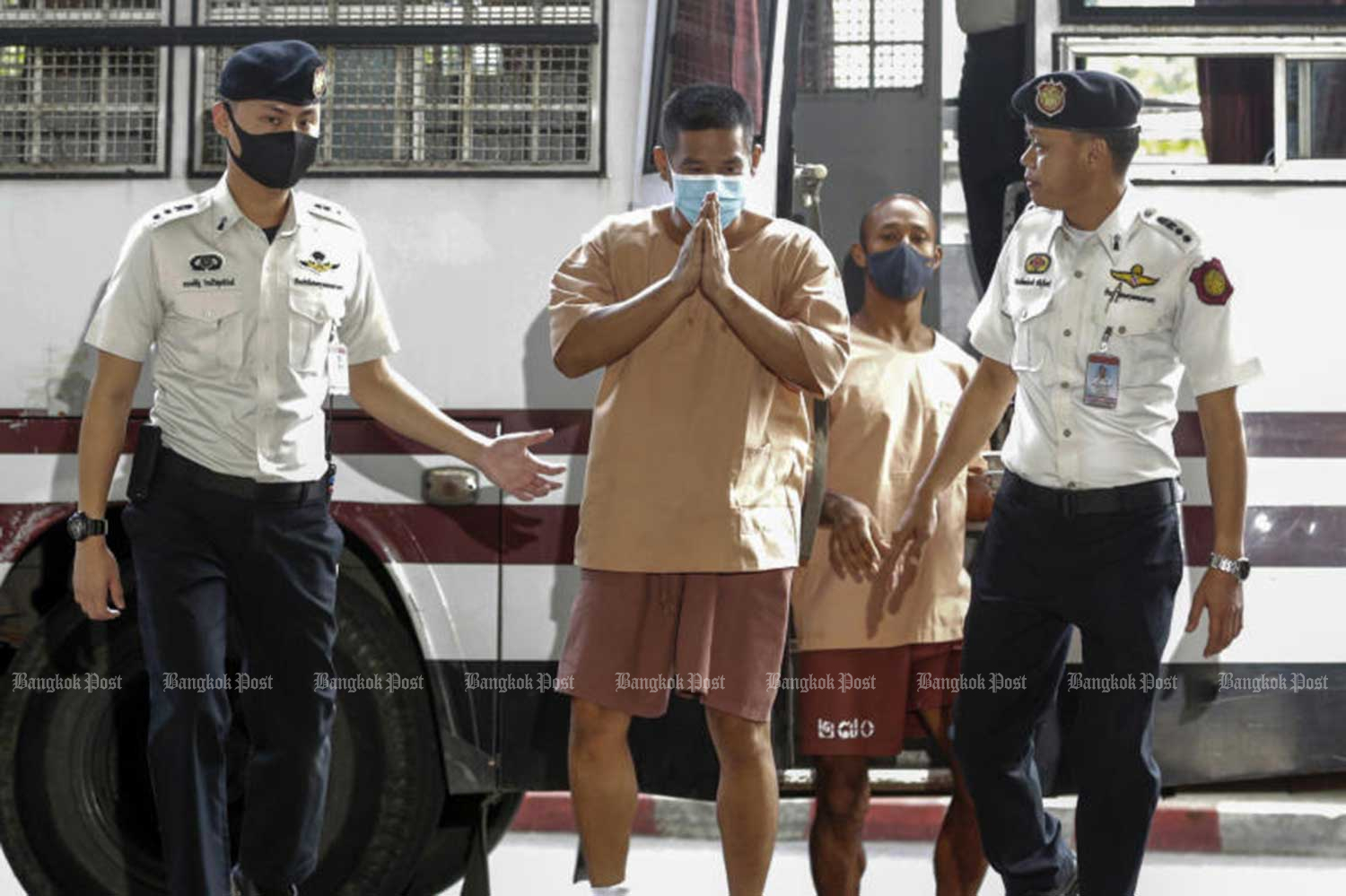 Prasittichai Khaokaew, 38, front centre, former director of a primary school in Sing Buri province, arrives at the Criminal Court in Bangkok on Thursday for sentencing for murder and robbery at a gold shop in Lop Buri province, in which a young boy and two adults were killed, on Jan 9. (Photo: Pornprom Satrabhaya)