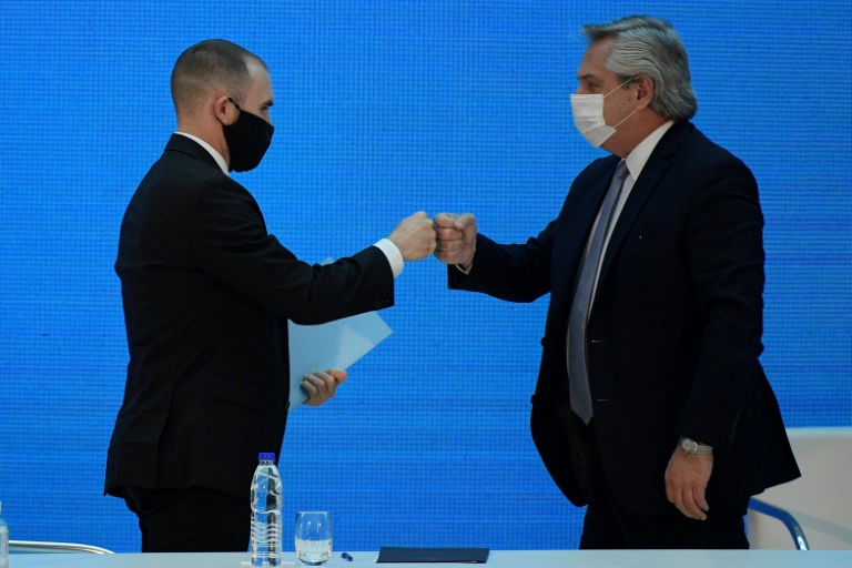 Argentina's President Alberto Fernandez (R) and Economy Minister Martin Guzman greet each other with a fist bump after announcing the restructuring of a $66 billion foreign-law debt Argentina's President Alberto Fernandez (R) and Economy Minister Martin Guzman greet each other with a fist bump after announcing the restructuring of a $66 billion foreign-law debt