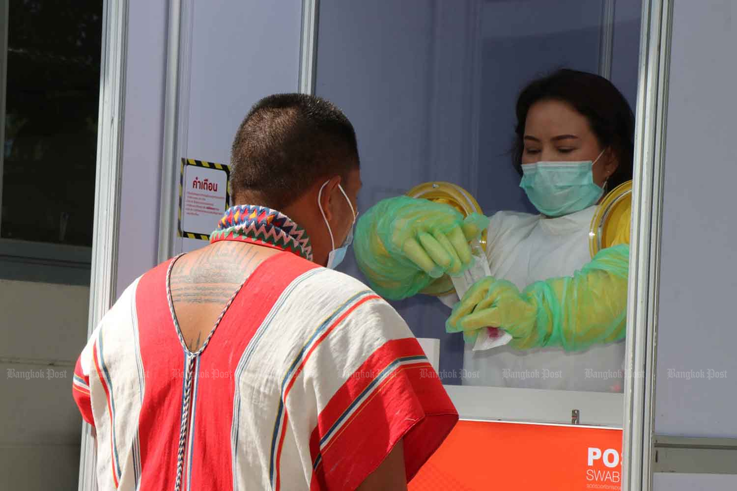 A health official collects a nasal swab from a migrant for a Covid-19 test, in Kanchanaburi province on Thursday. Photo by PIYARAT CHONGCHAROEN A health official collects a nasal swab from a migrant for a Covid-19 test, in Kanchanaburi province on Thursday. Photo by PIYARAT CHONGCHAROEN
