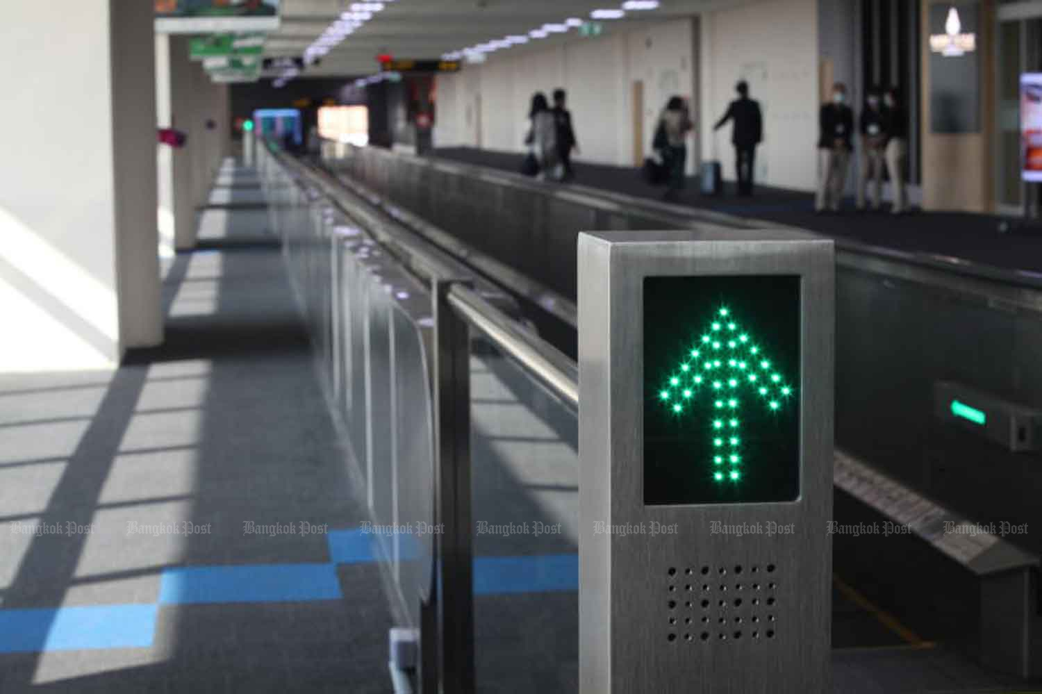 This moving walkway at Don Mueang airport, Bangkok, has few people in the absence of tourists. The cabinet on Tuesday resolved to welcome back long-stay foreign tourists, on condition they agree to quarantine and provide proof of payment of somewhere to stay. (Photo: Arnun Chonmahatrakool)